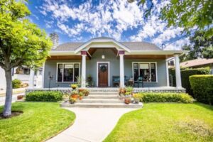 A small house featuring a front porch and a well-maintained lawn.